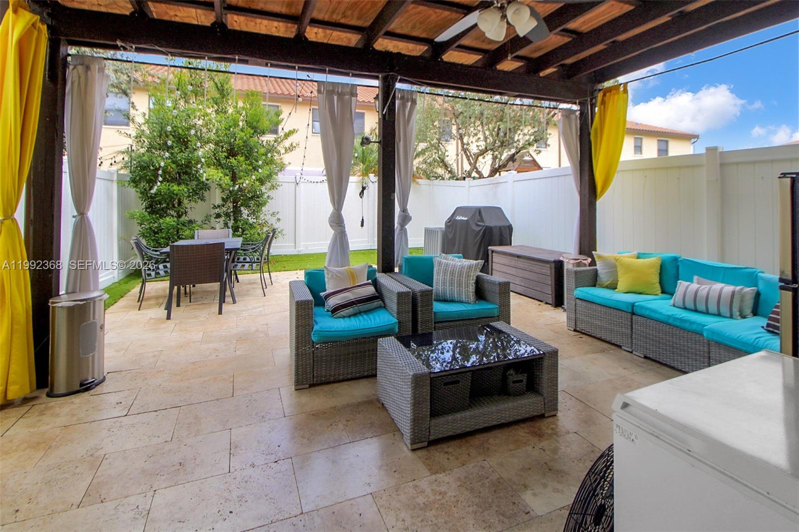 A covered patio features stone flooring, wicker furniture with turquoise cushions, and a dining area — 3323 W 90th Ter, Hialeah FL 33018, HIALEAH, FL