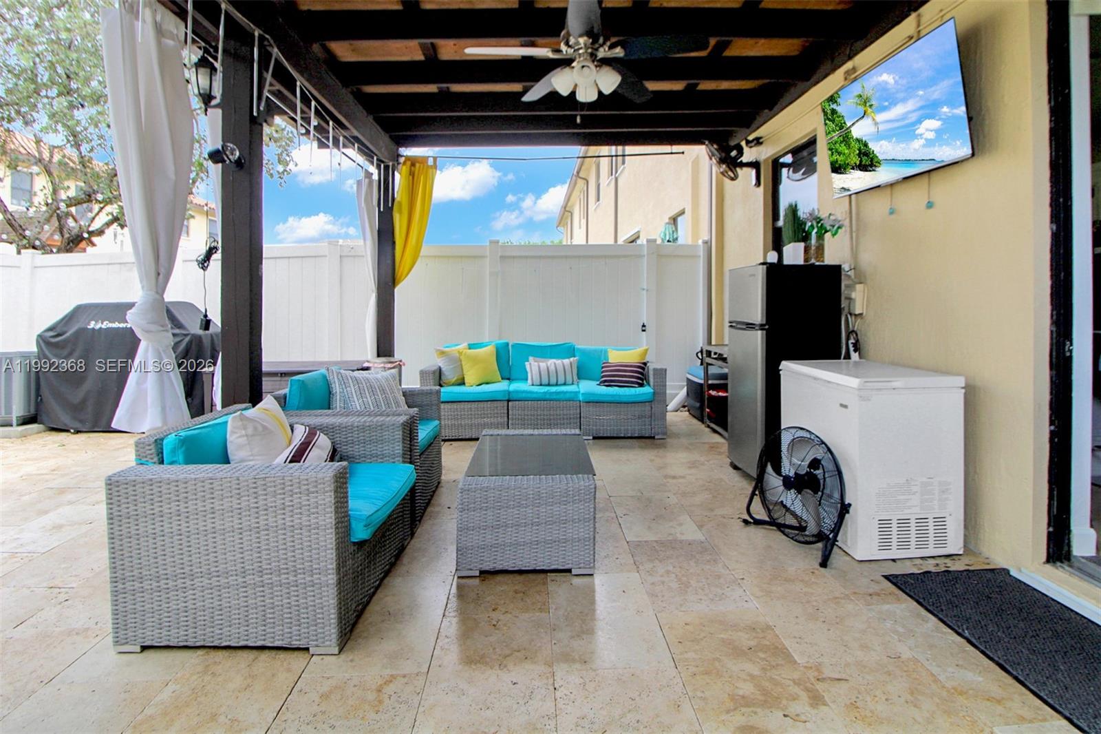 A covered outdoor patio features wicker furniture, a television, a refrigerator, and a chest freezer — 3323 W 90th Ter, Hialeah FL 33018, HIALEAH, FL