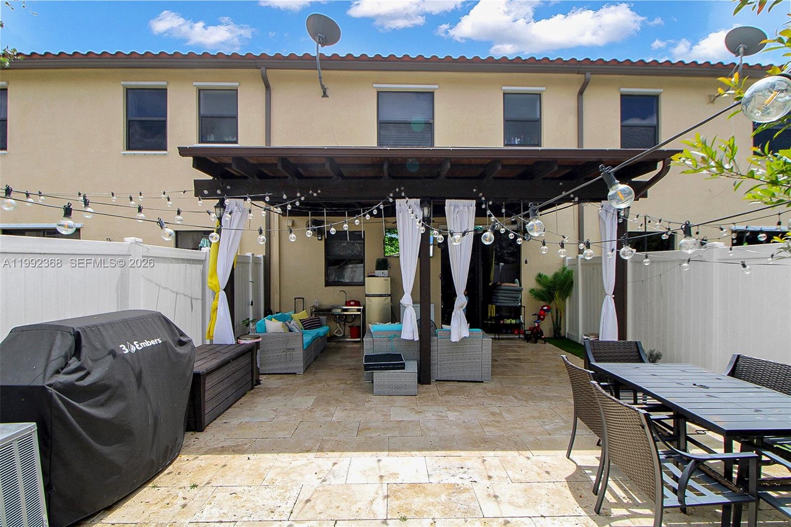 A paved backyard patio features a covered pergola, outdoor seating, a dining set, and string lights — 3323 W 90th Ter, Hialeah FL 33018, HIALEAH, FL