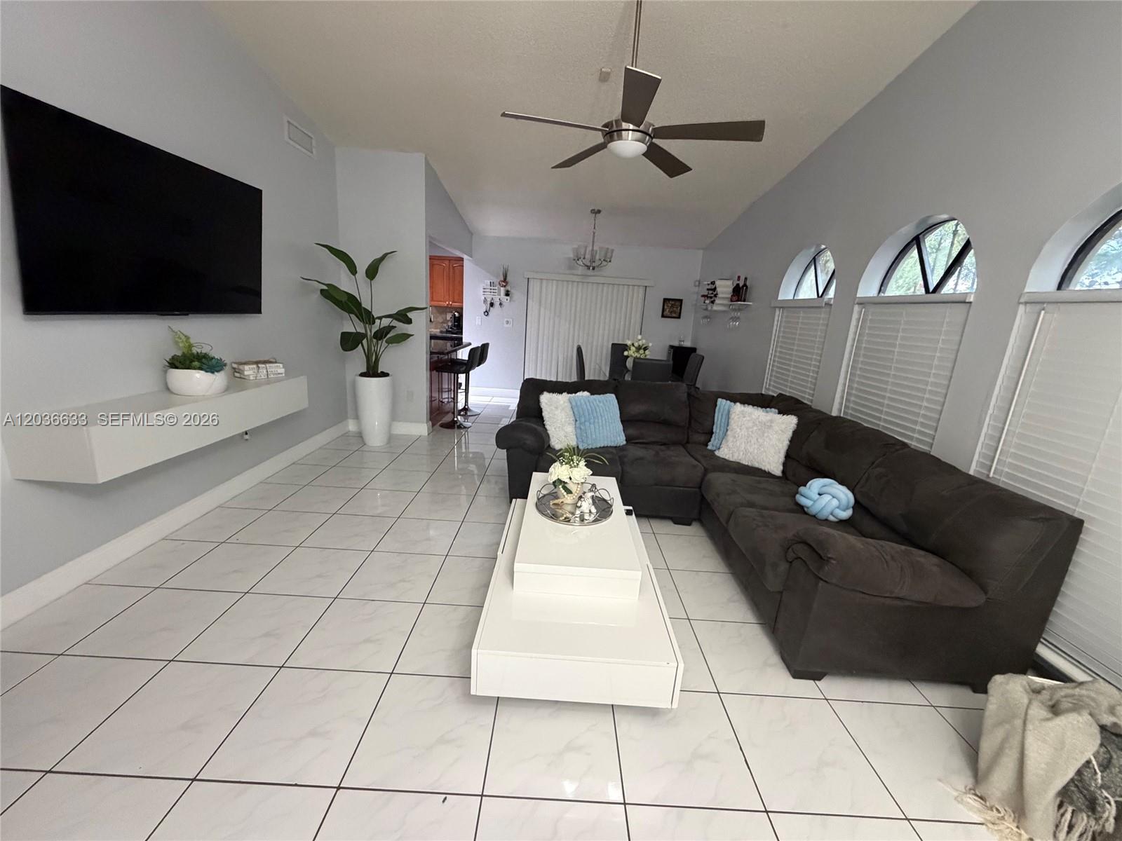 A living room features a dark sectional sofa, white tile floors, and a wall-mounted television — 5801 SW 144th Cir Pl # 5801, Miami FL 33183, MIAMI, FL