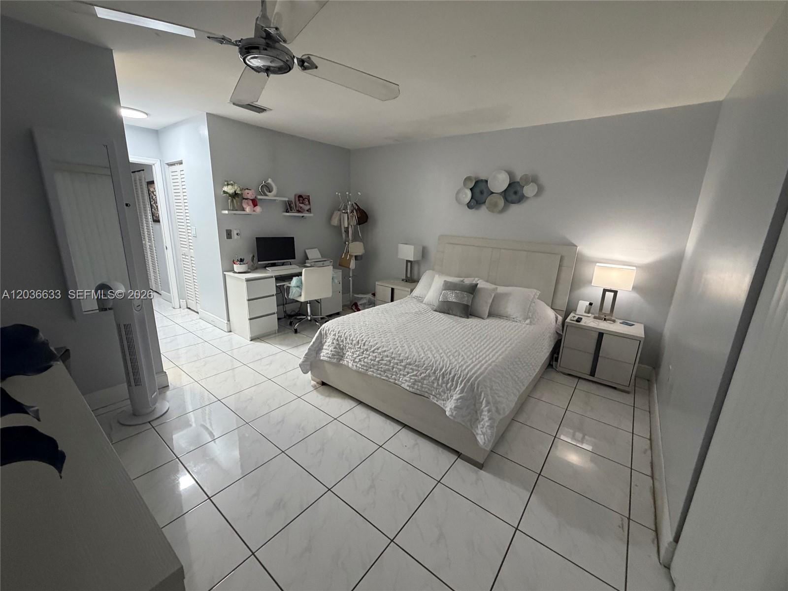 A bedroom features a white bed, a desk, and tiled floors under a ceiling fan — 5801 SW 144th Cir Pl # 5801, Miami FL 33183, MIAMI, FL