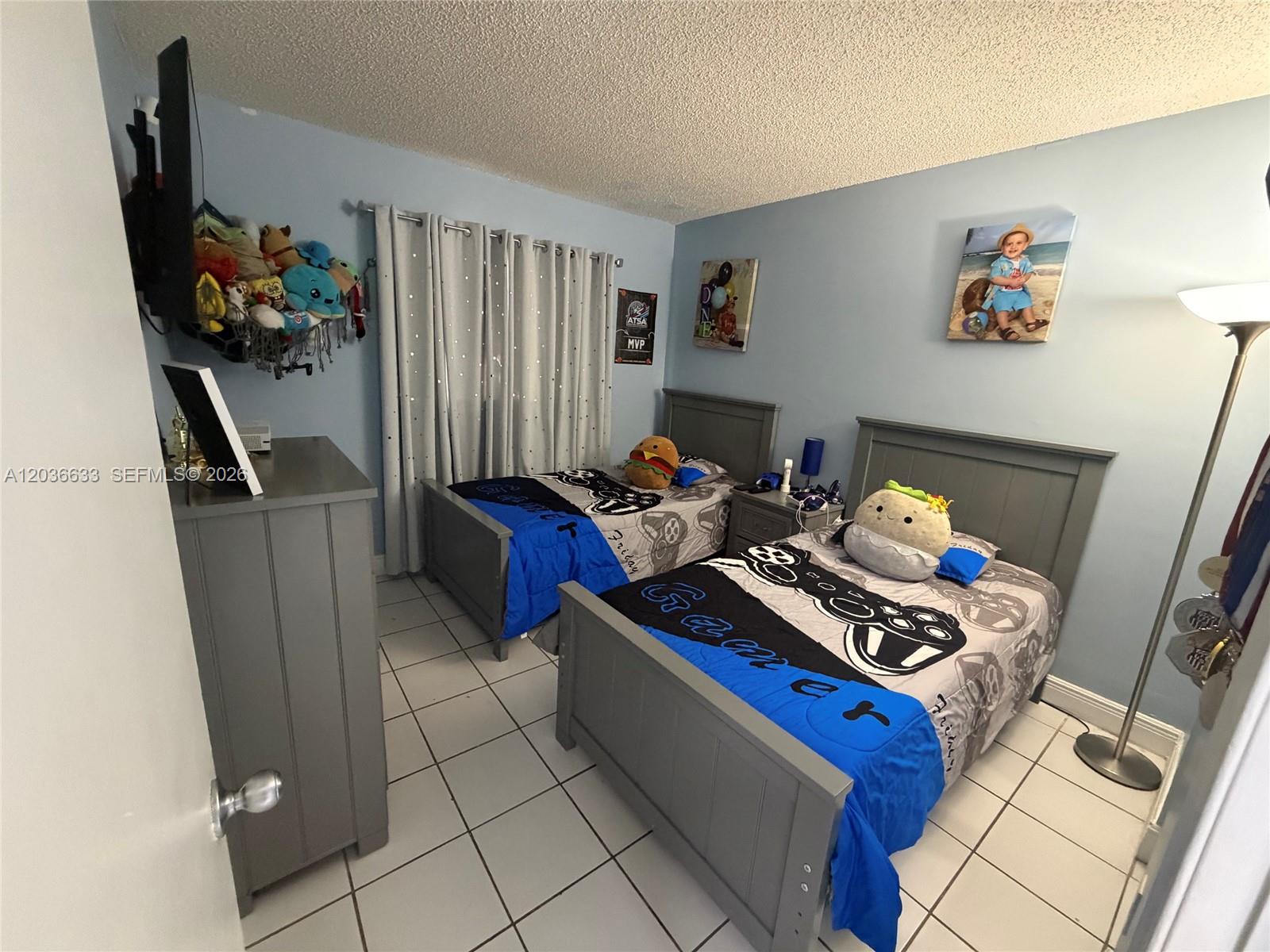 A bedroom with two twin beds, gray furniture, light blue walls, and tiled flooring — 5801 SW 144th Cir Pl # 5801, Miami FL 33183, MIAMI, FL