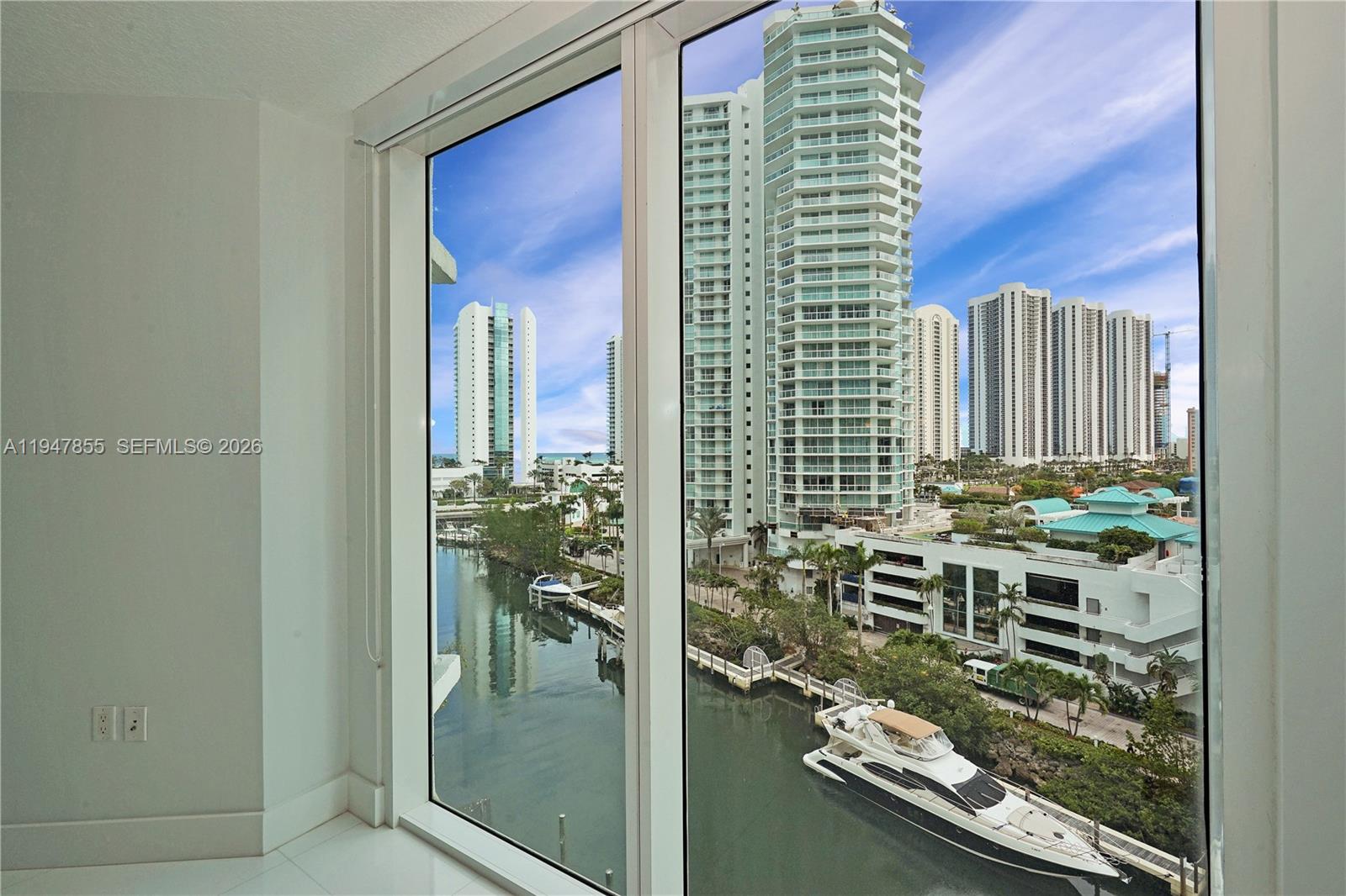A view of a canal, yachts, and high-rise buildings from a windowed room — SUNNY ISLES BEACH, FL