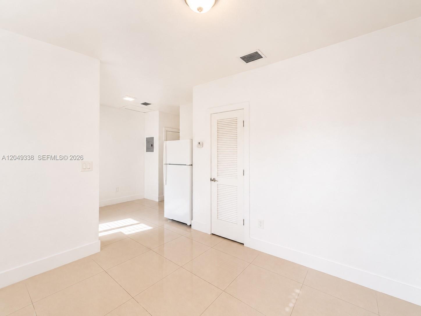 A white refrigerator stands next to a louvered door in a room with tiled floors — 1910 NW 31st St # 2, Miami FL 33142, MIAMI, FL