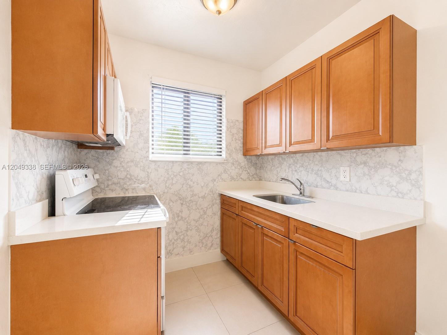 A kitchen features wood cabinets, white countertops, a marble-patterned backsplash, and stainless steel appliances — 1910 NW 31st St # 2, Miami FL 33142, MIAMI, FL