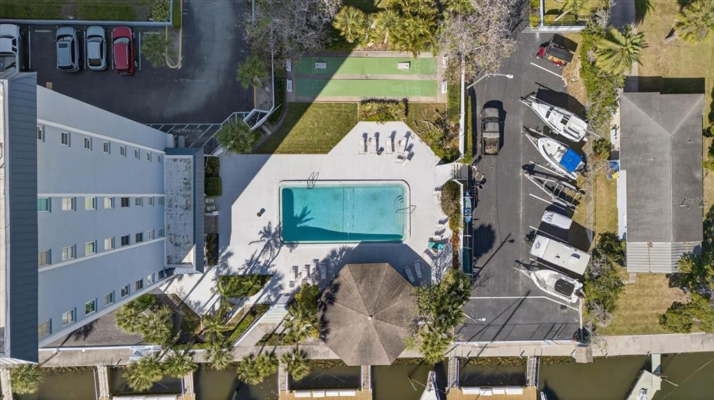 An aerial view shows a multi-story building, a swimming pool, shuffleboard courts, and boat slips — 4939 FLORAMAR TERRACE UNIT 710, NEW PORT RICHEY, FL