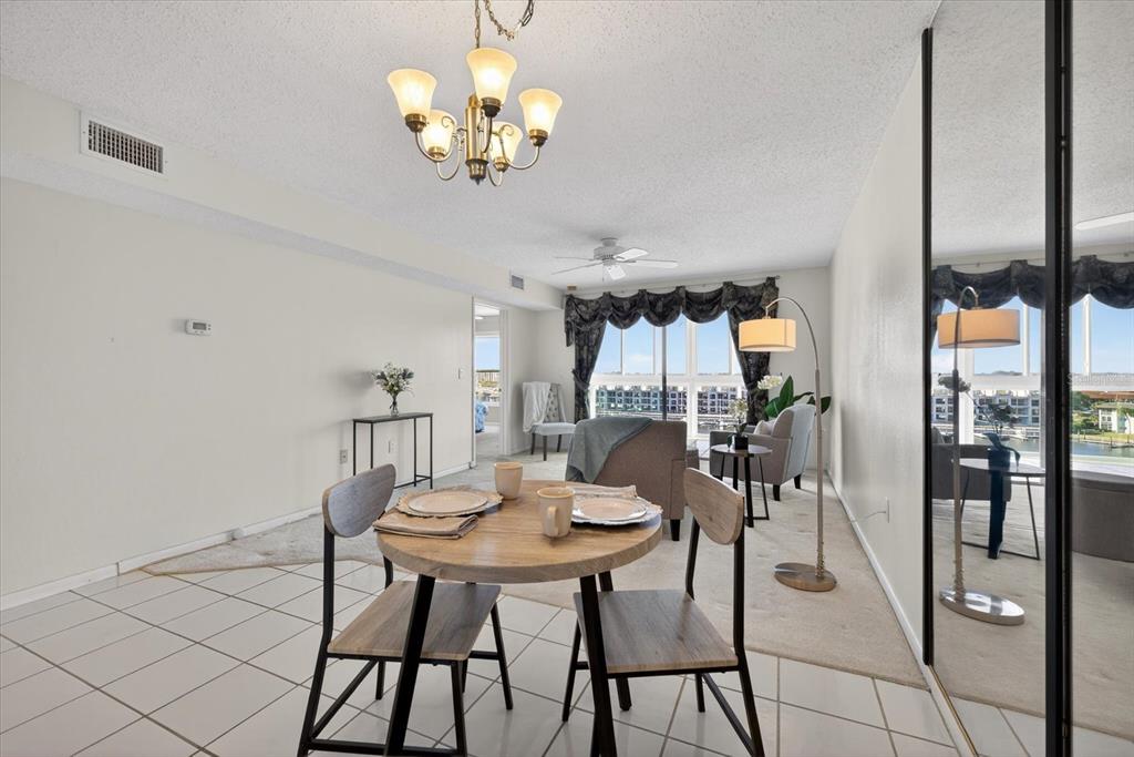 A dining area with a round table and chairs opens into a carpeted living room — 4939 FLORAMAR TERRACE UNIT 710, NEW PORT RICHEY, FL