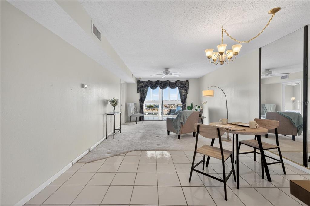 A dining area with tile flooring transitions into a carpeted living room with a balcony view — 4939 FLORAMAR TERRACE UNIT 710, NEW PORT RICHEY, FL