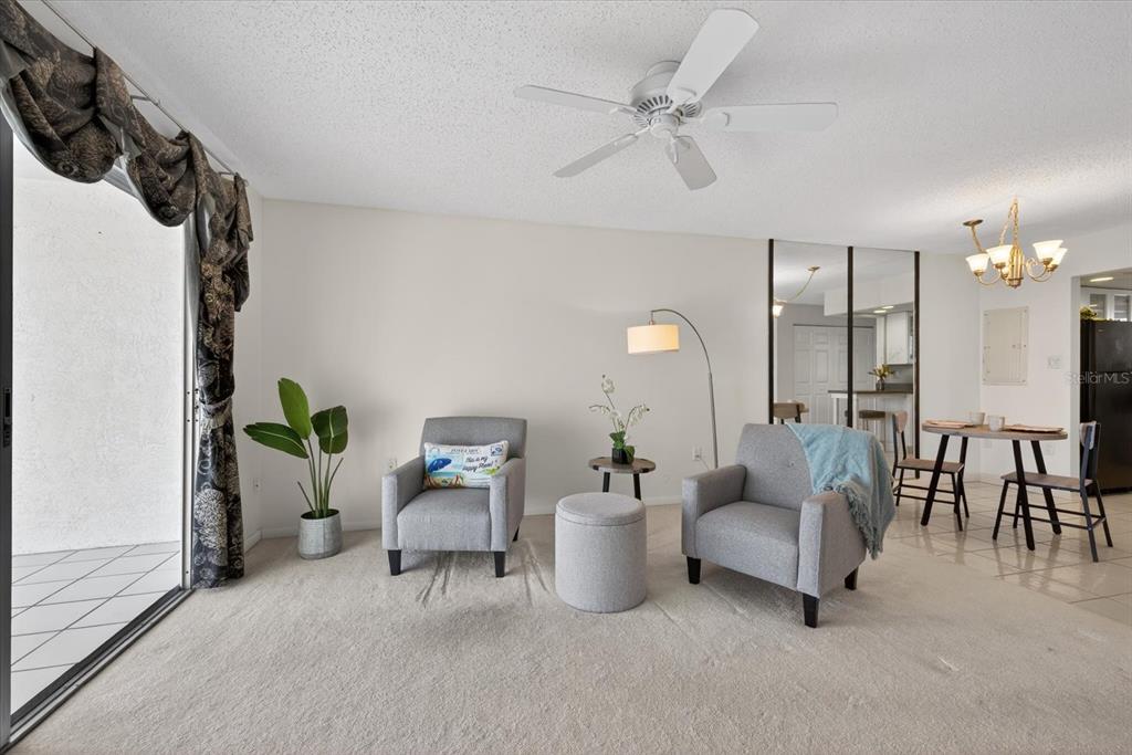 A living room with two gray armchairs, a floor lamp, and an adjacent dining area — 4939 FLORAMAR TERRACE UNIT 710, NEW PORT RICHEY, FL
