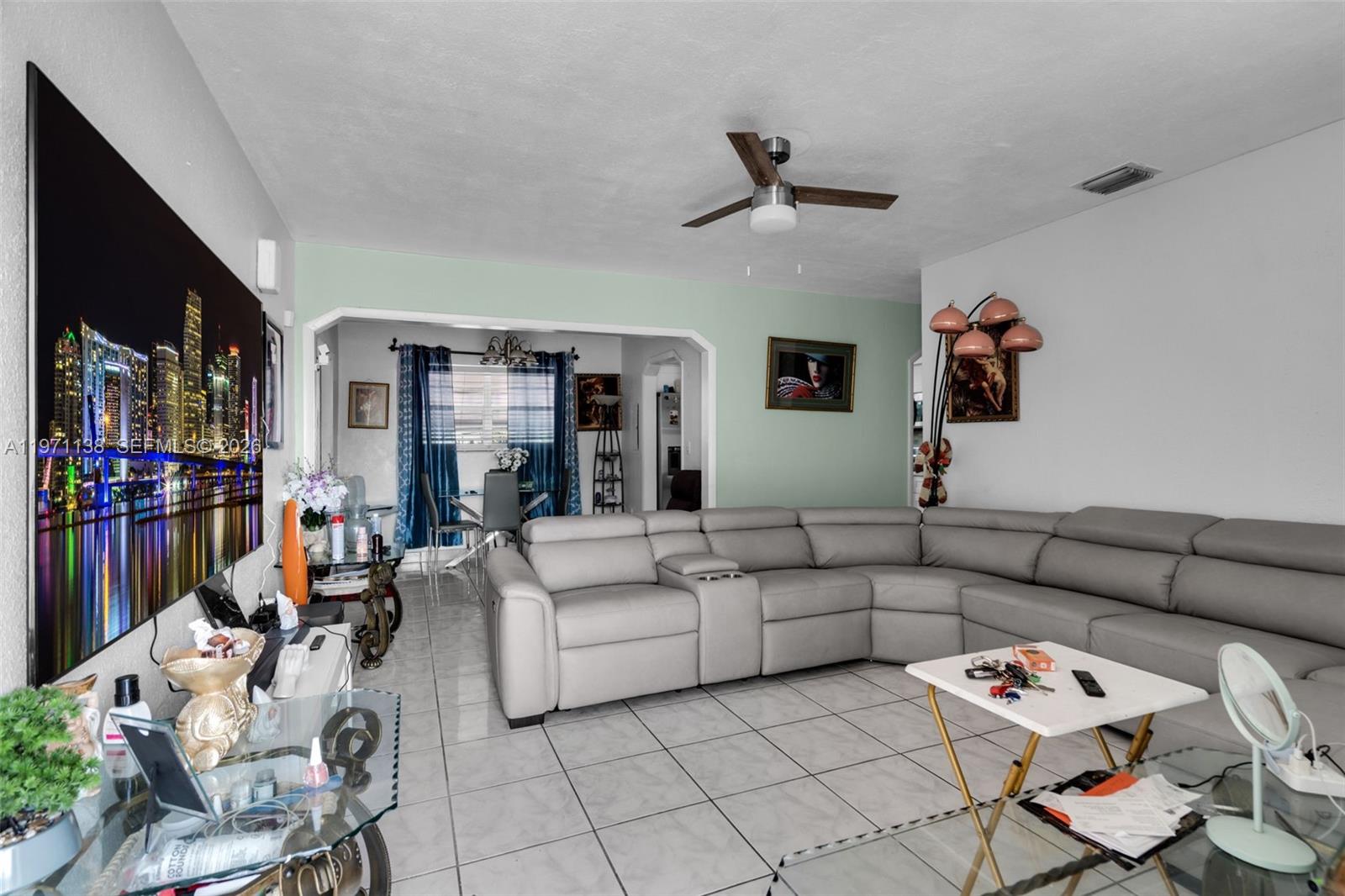 A living room features a large gray sectional sofa, tile flooring, and a wall-mounted television — 801 OPA LOCKA BLVD, Miami FL 33168, MIAMI, FL