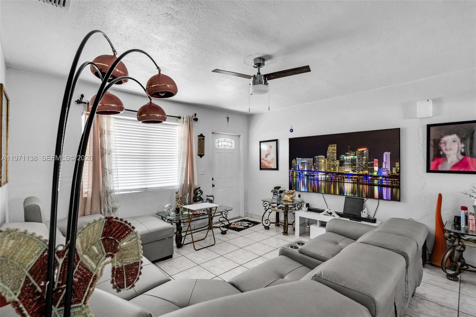 A living room features a large sectional sofa, a wall-mounted television, and tile flooring — 801 OPA LOCKA BLVD, Miami FL 33168, MIAMI, FL