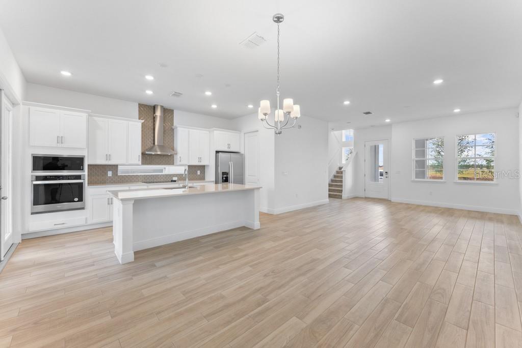 A modern kitchen with white cabinets and a center island opens to a living area — 10115 PEARSON AVENUE, ORLANDO, FL