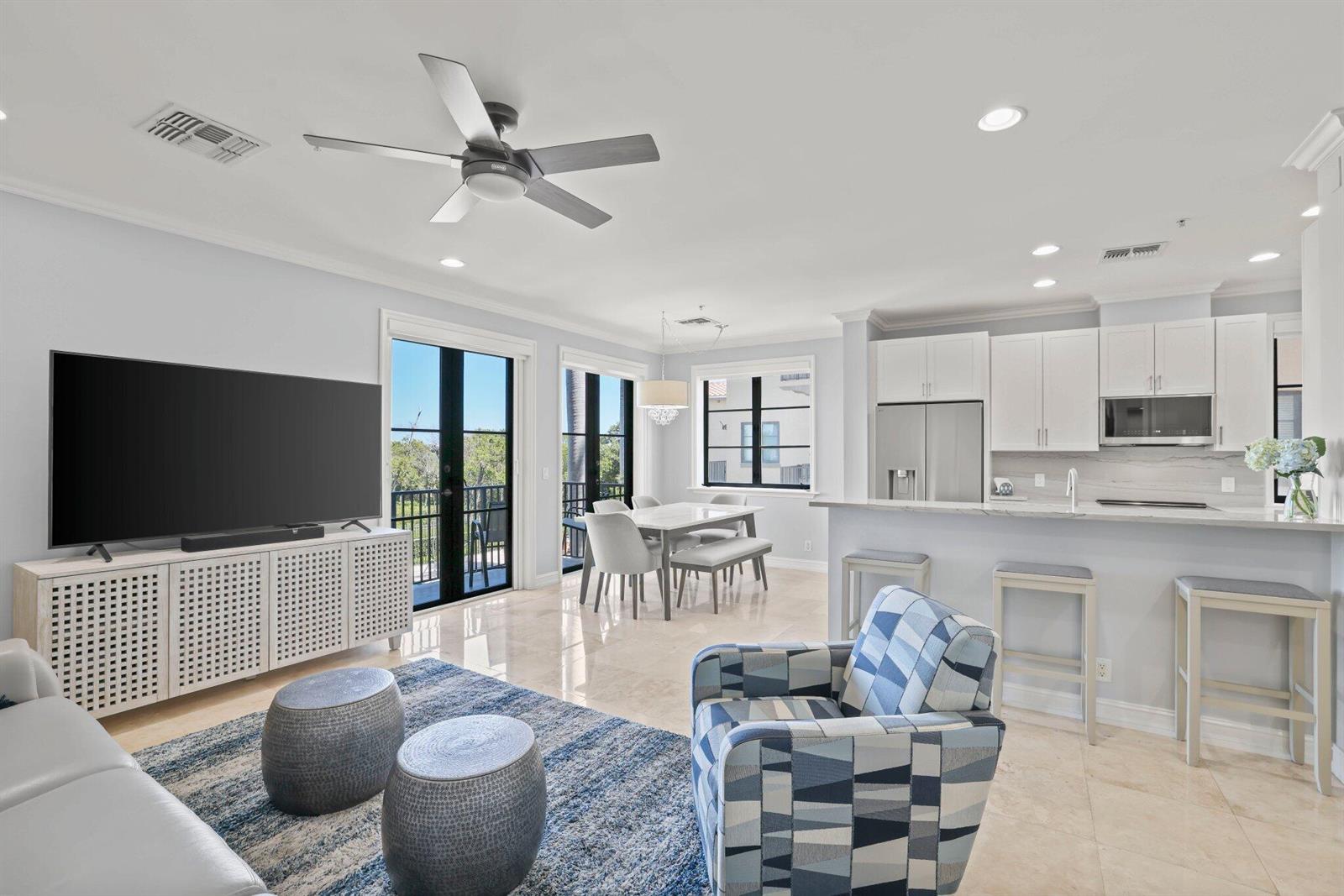 An open-concept living and dining area features a kitchen with white cabinets and tile flooring — 920 Via Villagio, Hypoluxo FL 33462, HYPOLUXO, FL