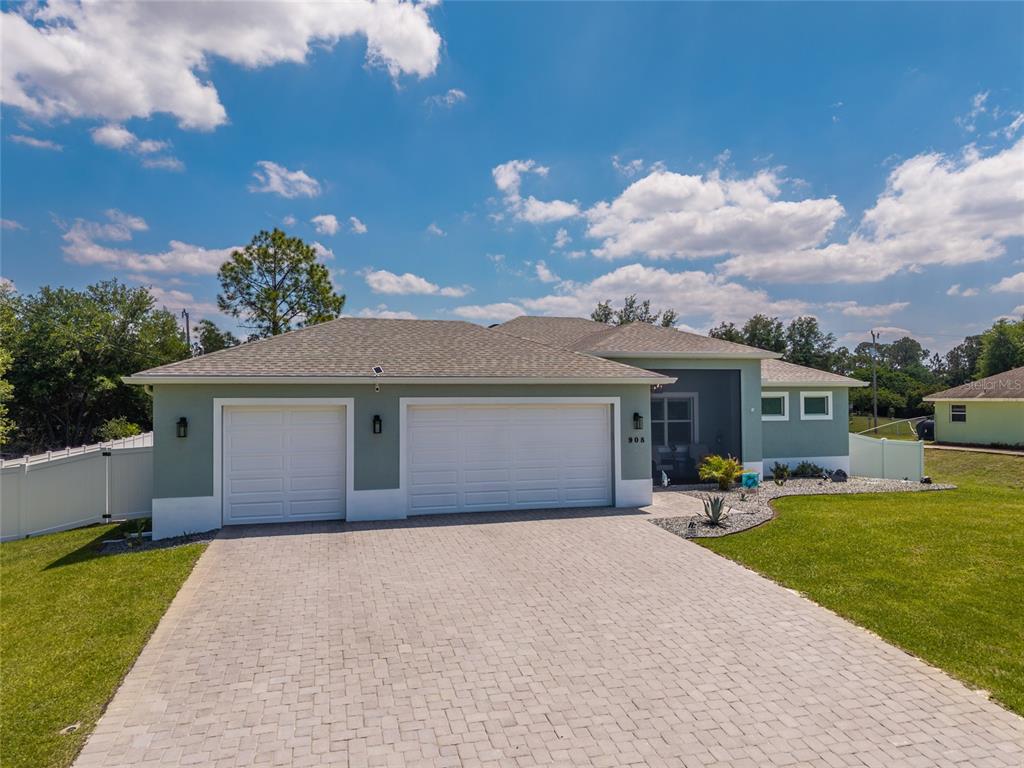 A single-story house with a paved driveway, two garage doors, and light green exterior walls — 908 HIBISCUS AVENUE, LEHIGH ACRES, FL