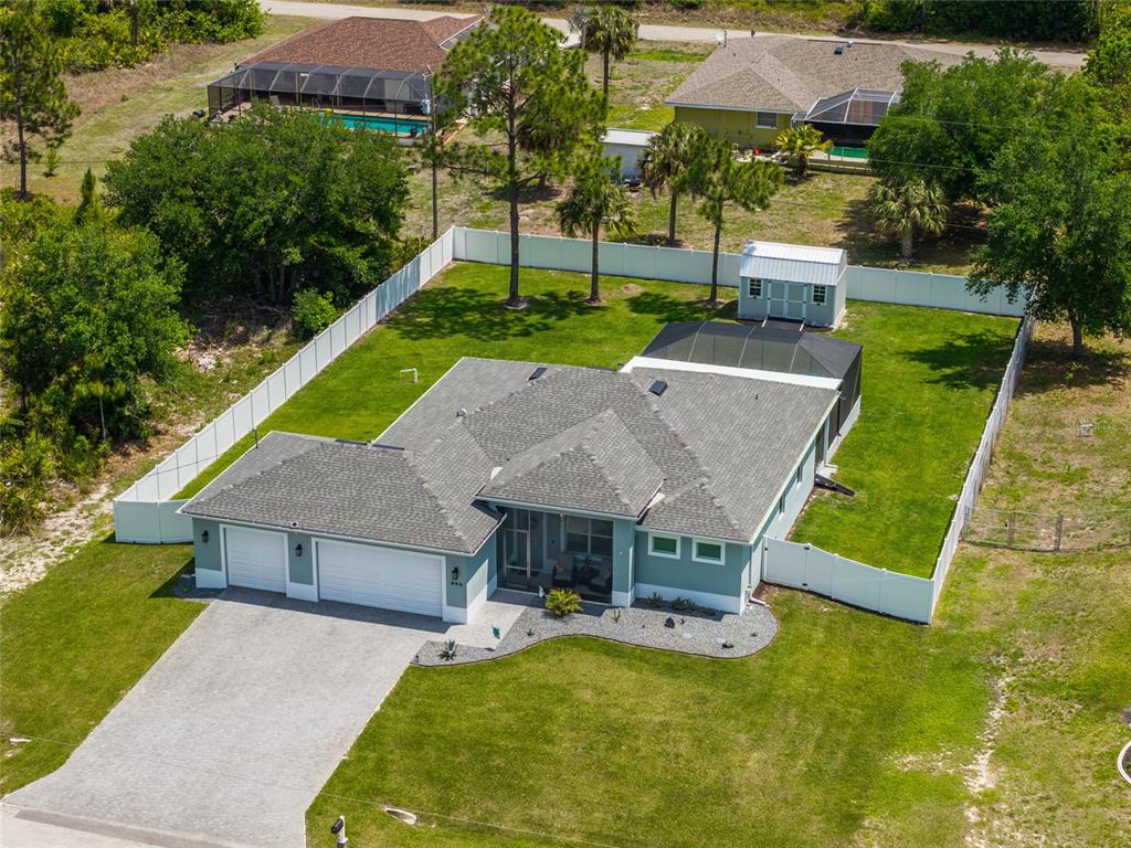 An aerial view shows a single-story house with a garage, fenced yard, and pool enclosure — 908 HIBISCUS AVENUE, LEHIGH ACRES, FL