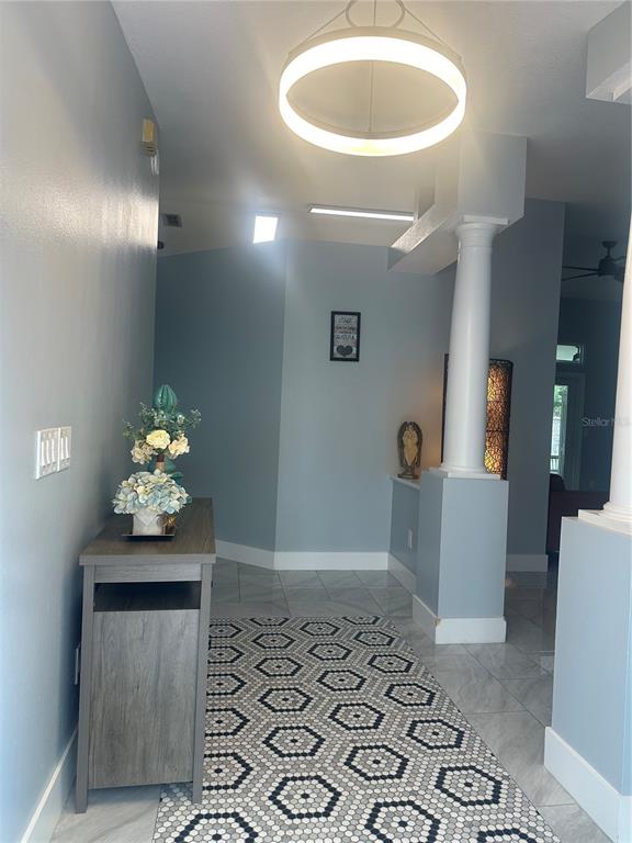 A foyer features a gray console table, a geometric patterned rug, and a white column — 10924 MILL POND WAY, ORLANDO, FL