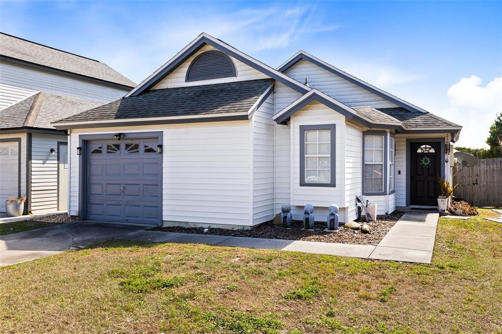 A single-story house with white siding, a gray garage door, and a front walkway — 9808 SURREY RIDGE ROAD, ORLANDO, FL