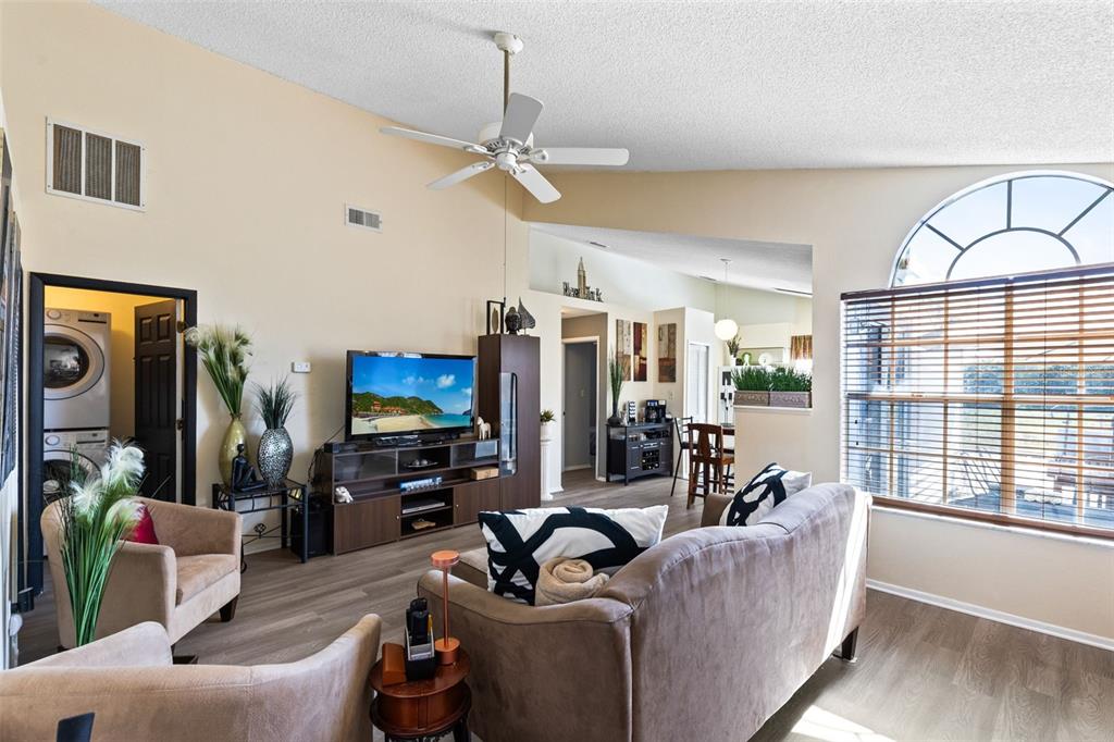 A living room with light-colored walls, wood-look flooring, a ceiling fan, and a large window — 9808 SURREY RIDGE ROAD, ORLANDO, FL