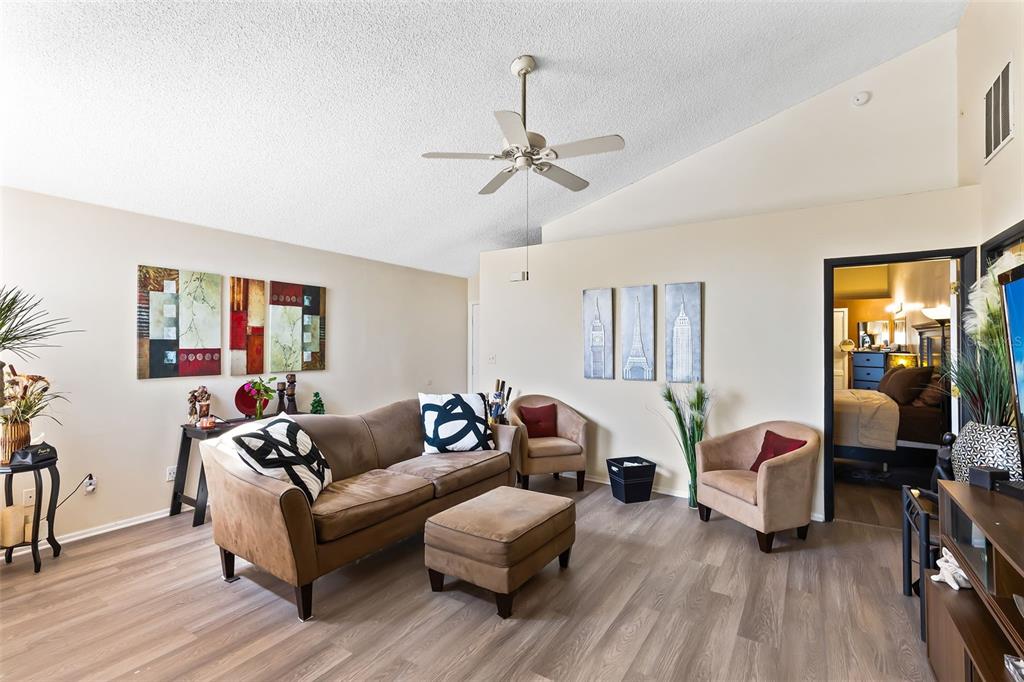 A living room features a brown sofa, two armchairs, a matching ottoman, and wood-look flooring — 9808 SURREY RIDGE ROAD, ORLANDO, FL