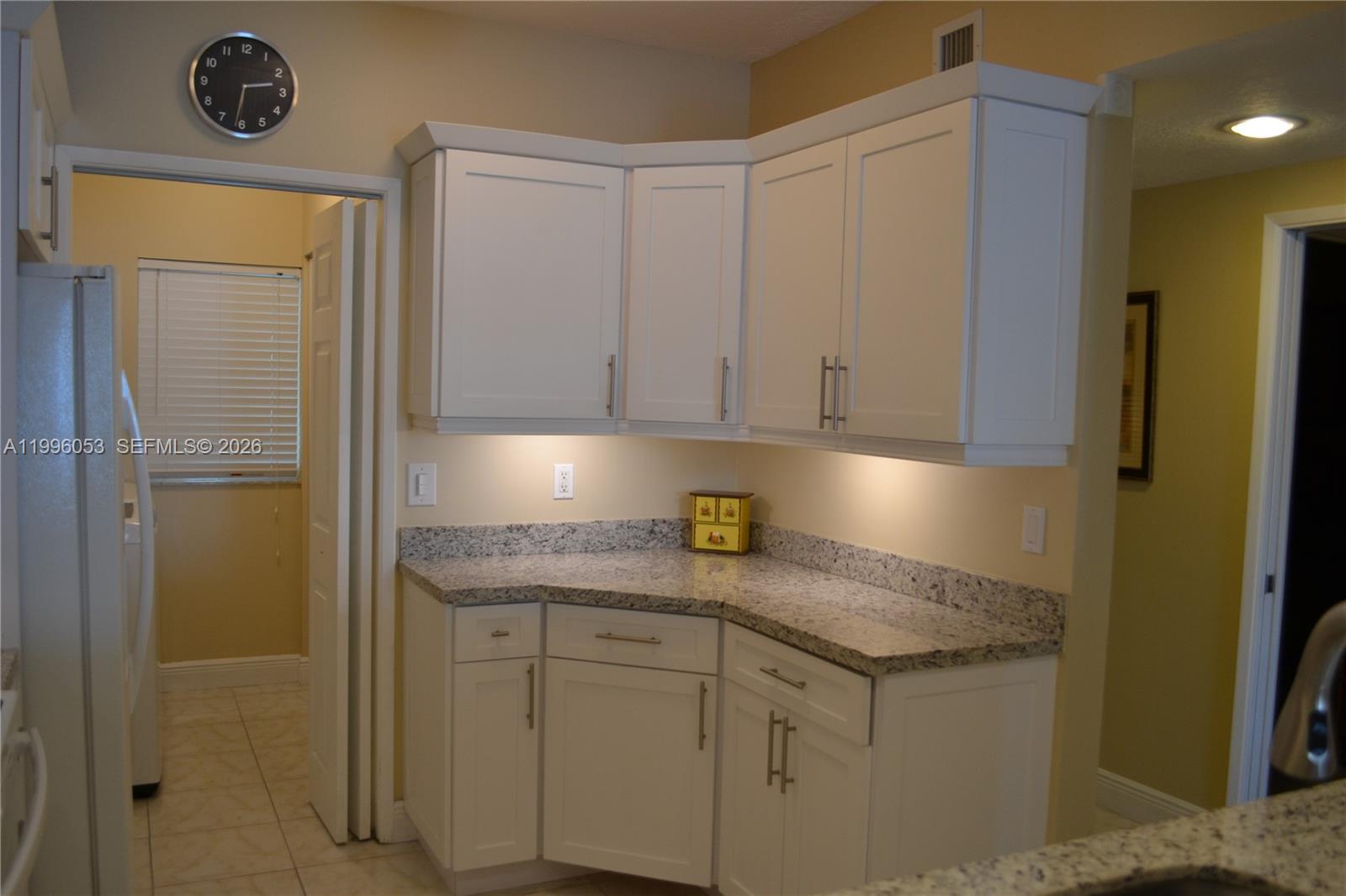 A kitchen corner features white cabinets, granite countertops, and under-cabinet lighting — SUNNY ISLES BEACH, FL
