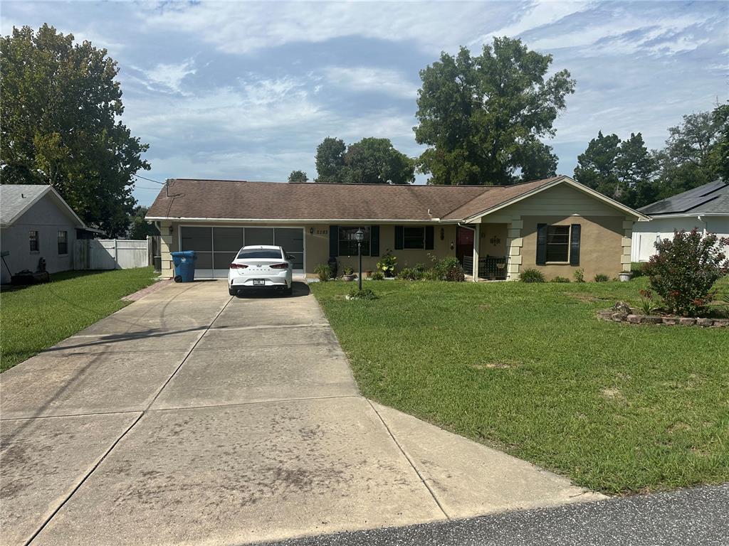 A single-story house with a concrete driveway, a white car, and a grassy front yard — 2283 RENTON LANE, SPRING HILL, FL