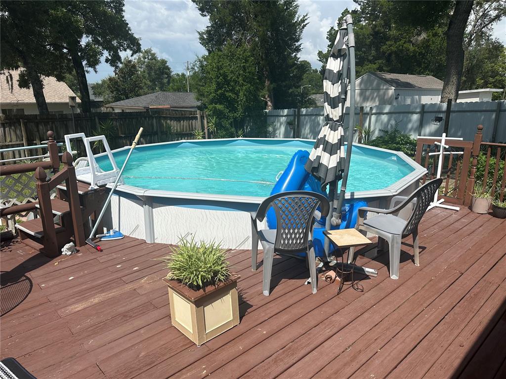 An above-ground swimming pool sits on a wooden deck with patio furniture and a fence — 2283 RENTON LANE, SPRING HILL, FL