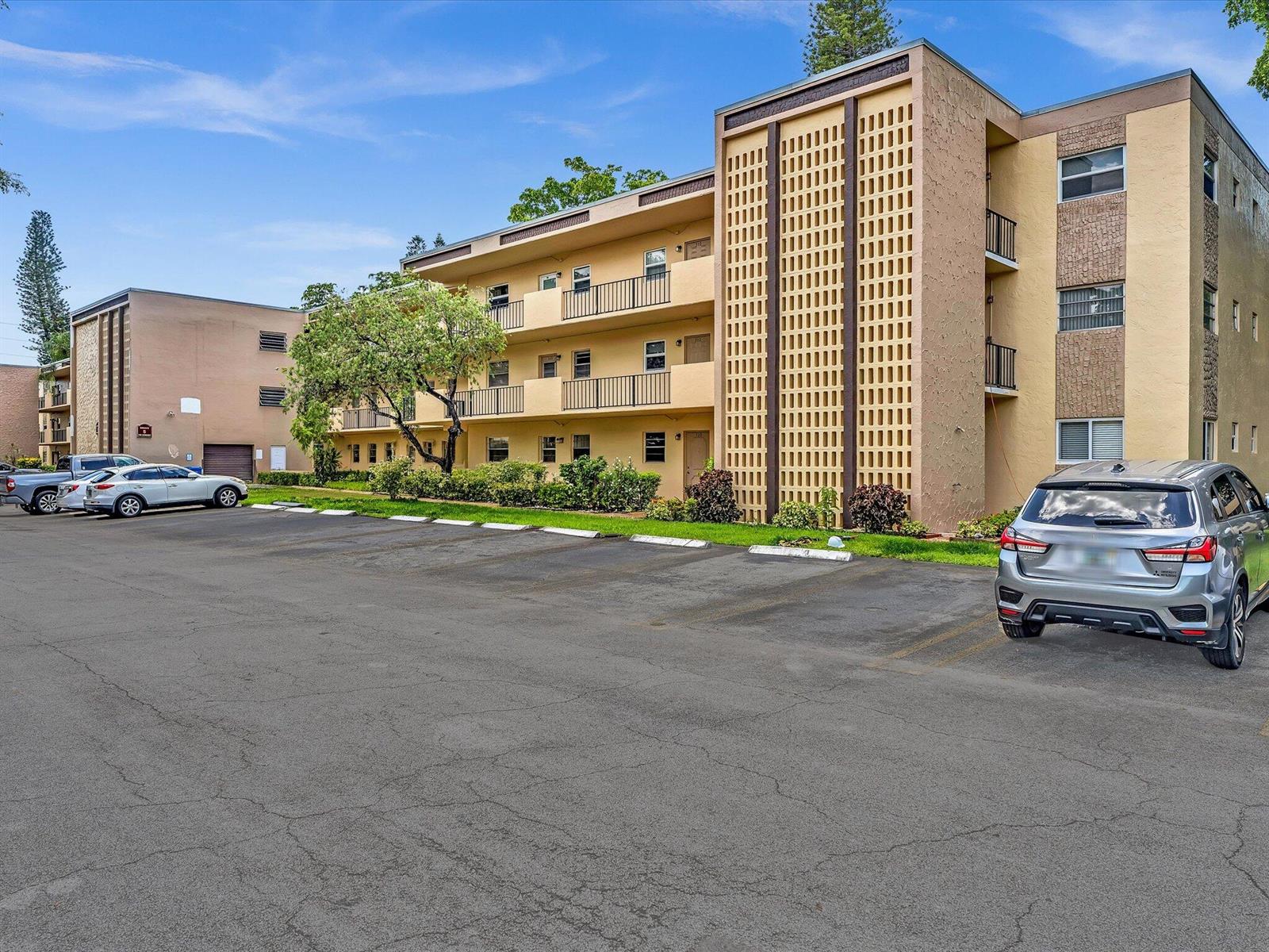 A multi-story apartment building with a parking lot in the foreground — 100 Ashbury Road # 103, Hollywood FL 33024, HOLLYWOOD, FL