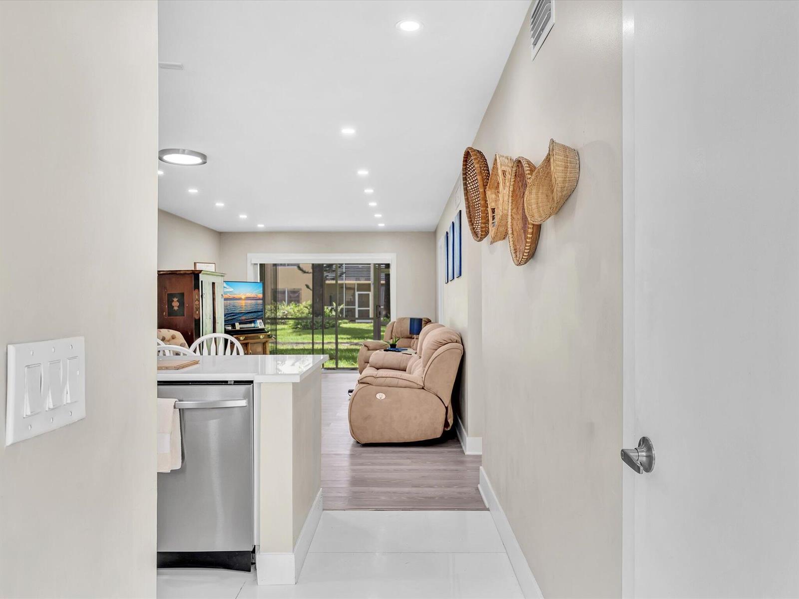 A view from a hallway into a living room with a kitchen island and patio — 100 Ashbury Road # 103, Hollywood FL 33024, HOLLYWOOD, FL