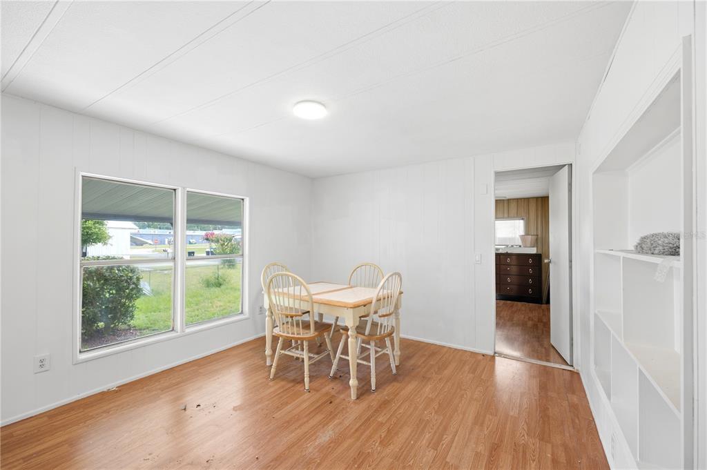 A dining room with white paneled walls, wood-look flooring, a small table, and built-in shelving — 7321 WINDY WAY, BROOKSVILLE, FL