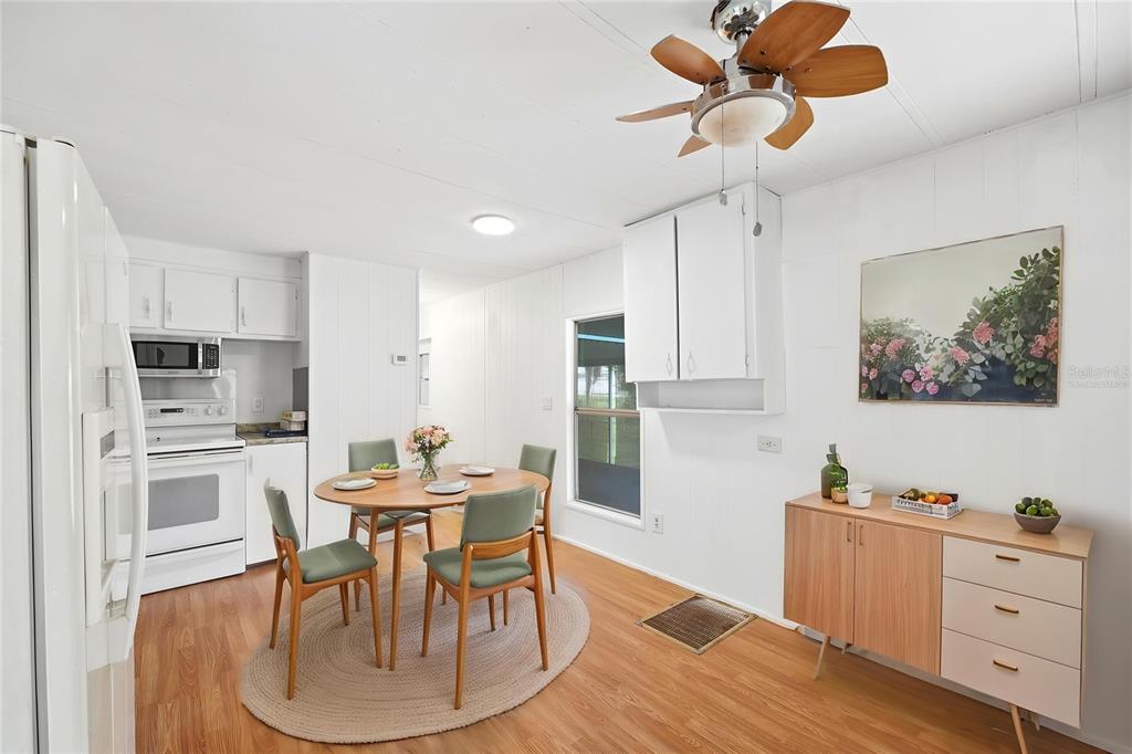 A dining area with a round table, four green chairs, and a wooden sideboard — 7321 WINDY WAY, BROOKSVILLE, FL