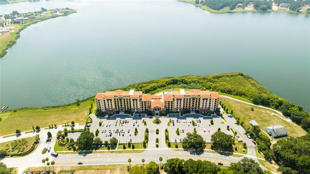 An aerial view shows a large multi-story apartment complex situated beside a lake — 16300 COUNTY ROAD 455 UNIT 606, MONTVERDE, FL