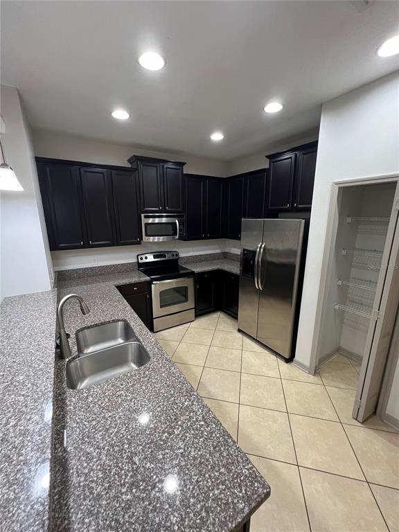 A kitchen features dark wood cabinets, granite countertops, stainless steel appliances, and tile flooring — 9157 SHEPTON STREET, ORLANDO, FL