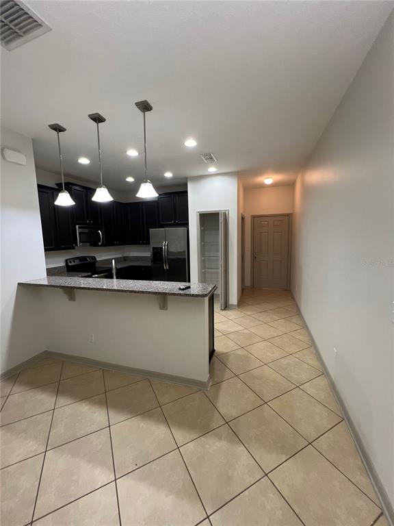A kitchen features dark cabinets, granite countertops, a breakfast bar, and tile flooring — 9157 SHEPTON STREET, ORLANDO, FL