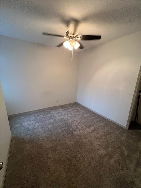 An empty bedroom features neutral walls, beige carpeting, and a ceiling fan with lights — 9157 SHEPTON STREET, ORLANDO, FL