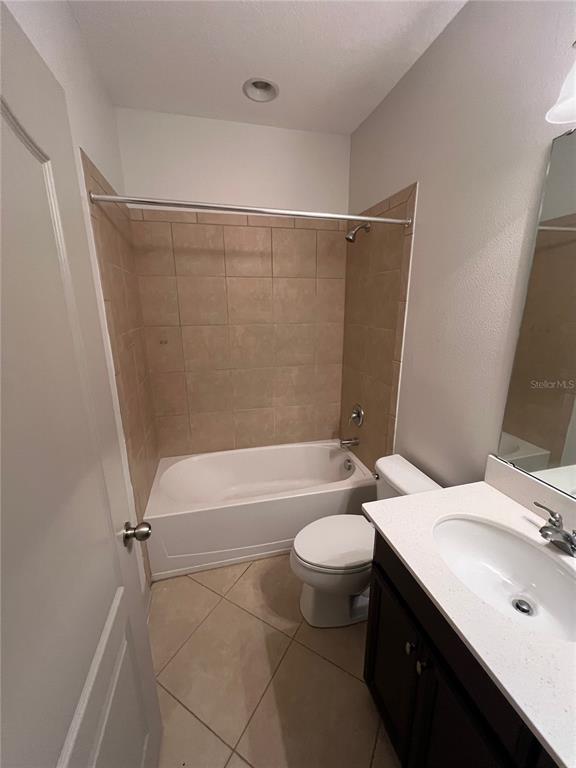A bathroom features a tiled shower-tub combination, a white toilet, and a vanity with a sink — 9157 SHEPTON STREET, ORLANDO, FL