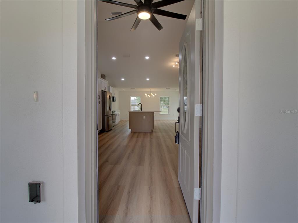 An open-concept kitchen and living area are viewed through an open front door — 9721 BAHIA ROAD, OCALA, FL