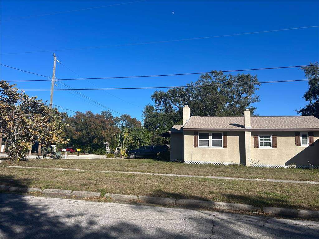 A tan, single-story house with a shingled roof sits behind a grassy front yard — 3324 W MARLIN AVENUE, TAMPA, FL