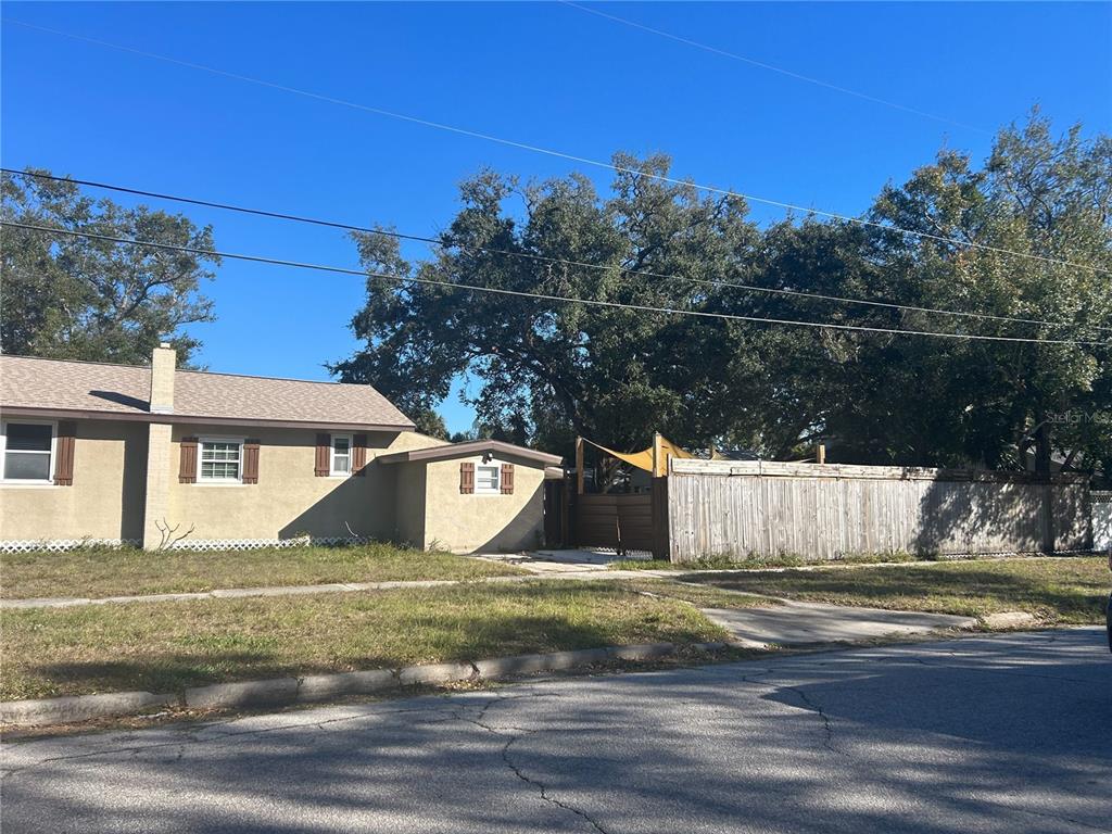 A single-story tan house with a wooden fence and large trees in the yard — 3324 W MARLIN AVENUE, TAMPA, FL