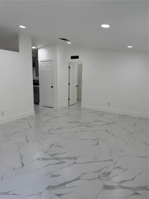A room with white walls, recessed lighting, and large white marble-patterned floor tiles — 15898 PEACE BOULEVARD, SPRING HILL, FL