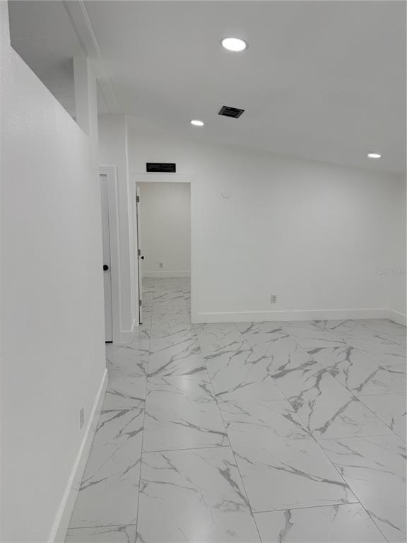 A room with white walls, recessed lighting, and white marble-patterned tile flooring — 15898 PEACE BOULEVARD, SPRING HILL, FL