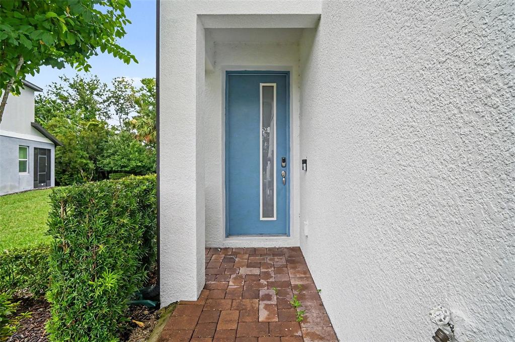 A blue front door with a vertical glass panel is set within a white stucco entryway — 1427 BROAD WING LANE, WINTER PARK, FL