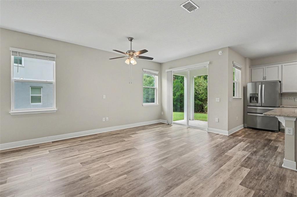 An open-concept living area features light-colored walls, wood-look flooring, a ceiling fan, and sliding doors — 1427 BROAD WING LANE, WINTER PARK, FL