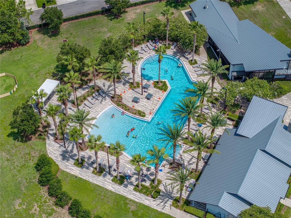 An aerial view shows a swimming pool with palm trees and surrounding buildings — 14501 PROMENADE PARKWAY, ODESSA, FL