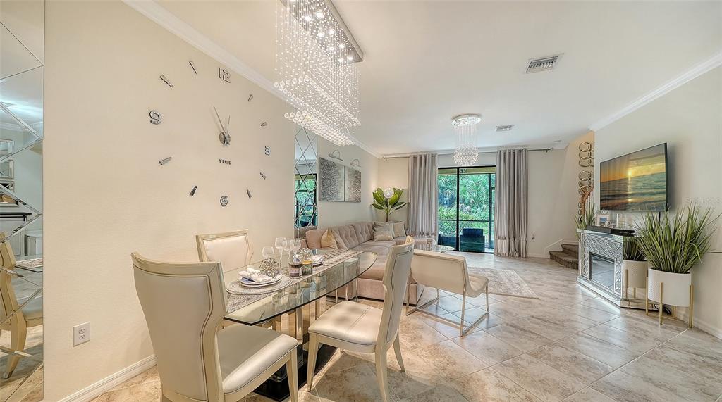 A dining and living area features a glass table, large wall clock, and mirrored fireplace — 20310 LAGENTE CIRCLE, VENICE, FL