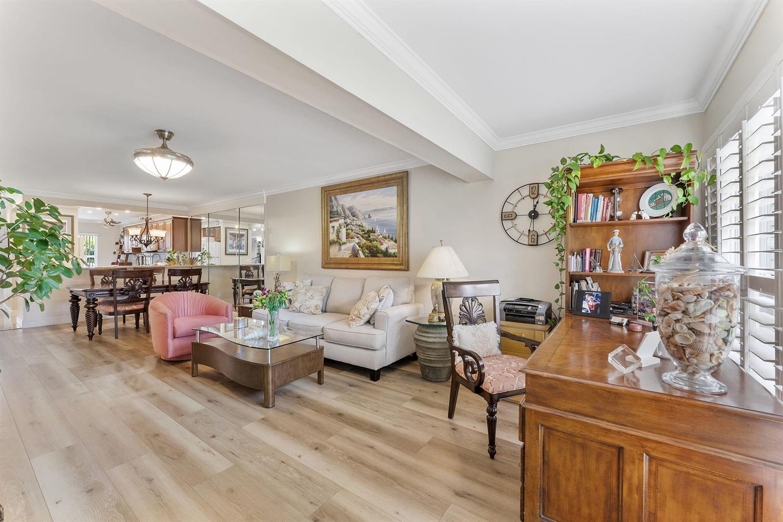 A living room features light wood flooring, a beige sofa, and a wooden desk area — 1041 Orange Terrace # 104, Delray Beach FL 33445, DELRAY BEACH, FL