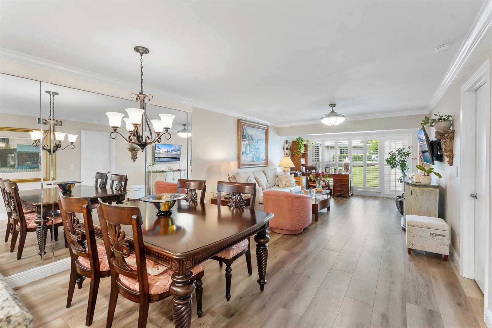 A dining area with a wooden table and mirror wall opens into a living room — 1041 Orange Terrace # 104, Delray Beach FL 33445, DELRAY BEACH, FL
