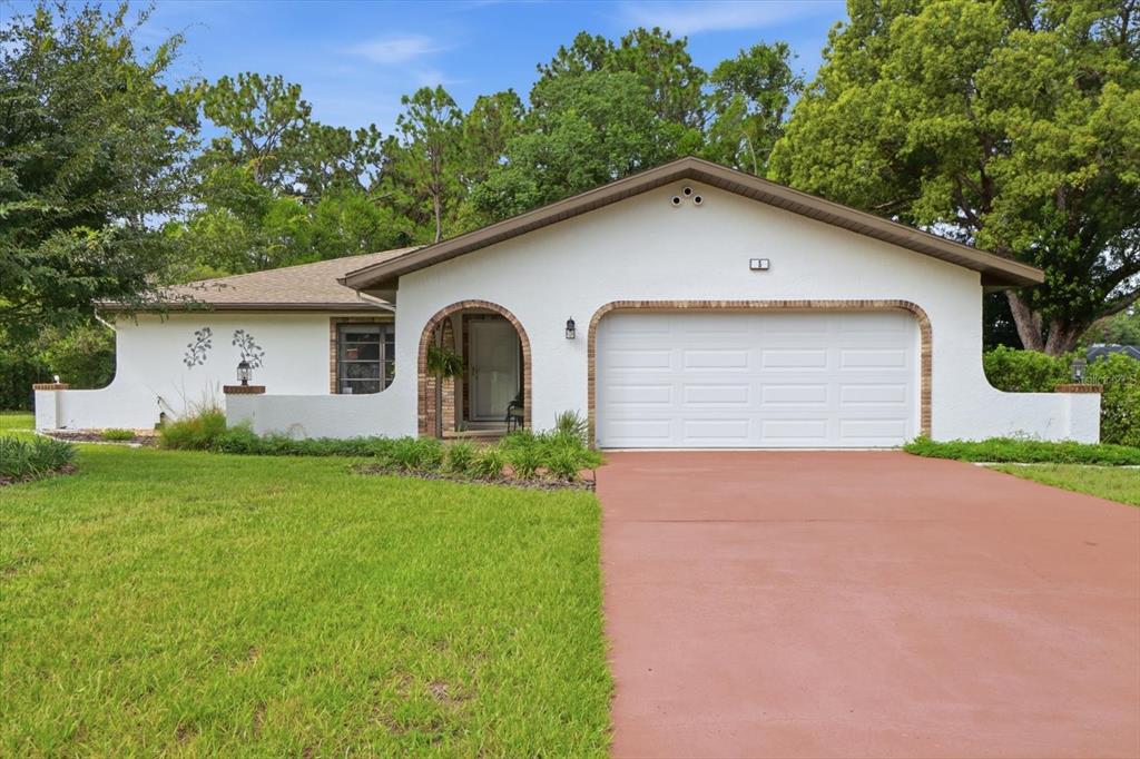 A single-story white house with a brick-arched entryway and a two-car garage — 5 DAHOON DRIVE, HOMOSASSA, FL