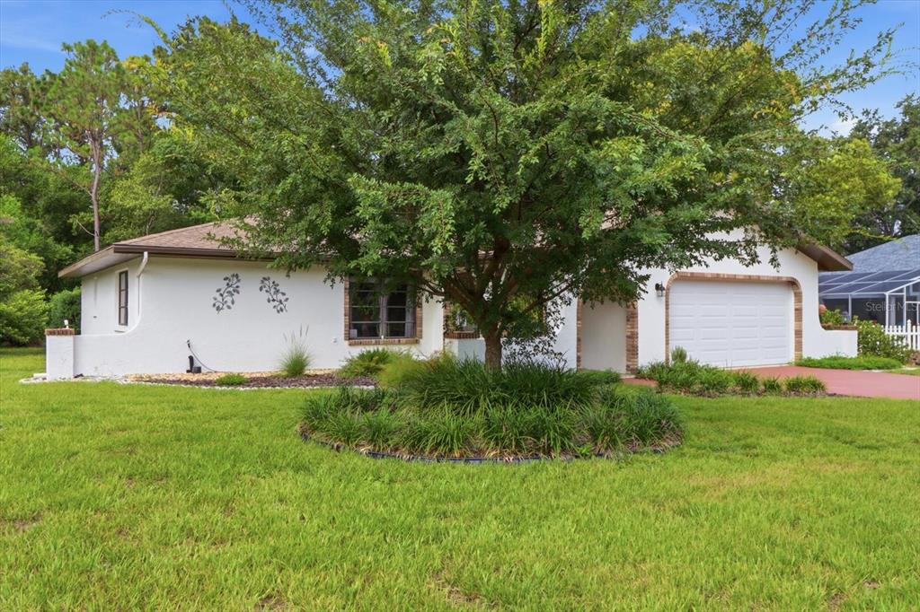 A white single-story house with a garage and a large tree in the front yard — 5 DAHOON DRIVE, HOMOSASSA, FL