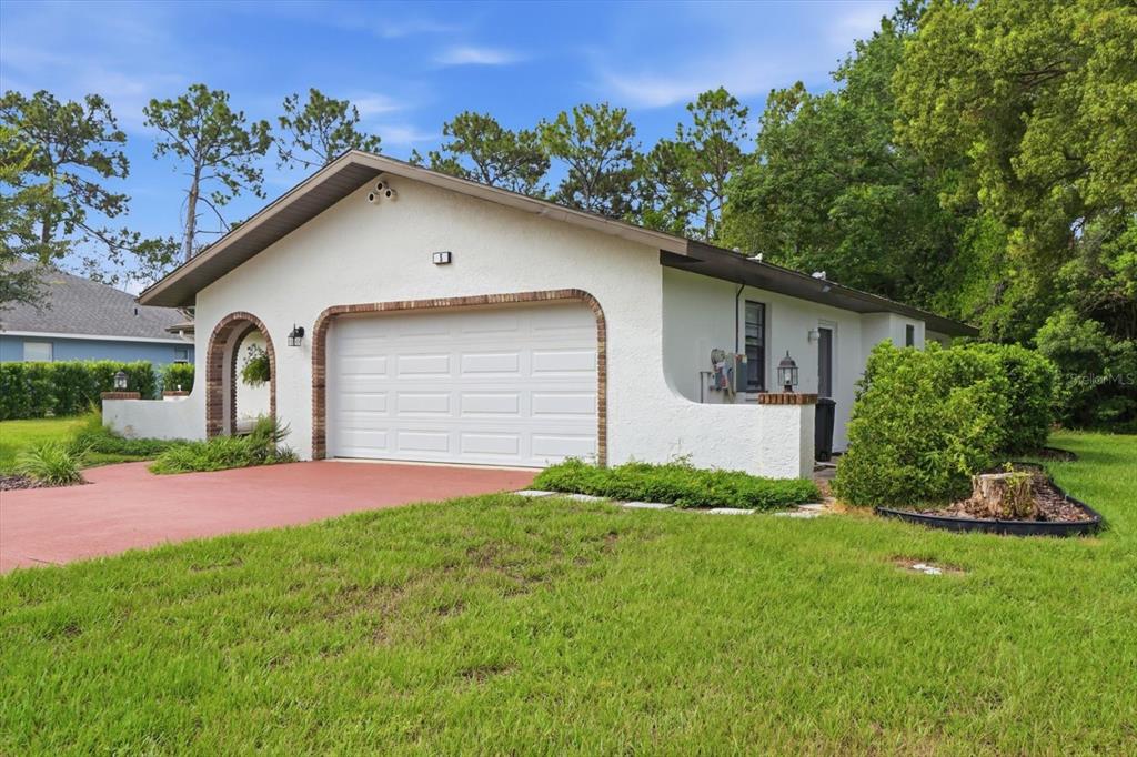 A white stucco house with a two-car garage and a red driveway — 5 DAHOON DRIVE, HOMOSASSA, FL