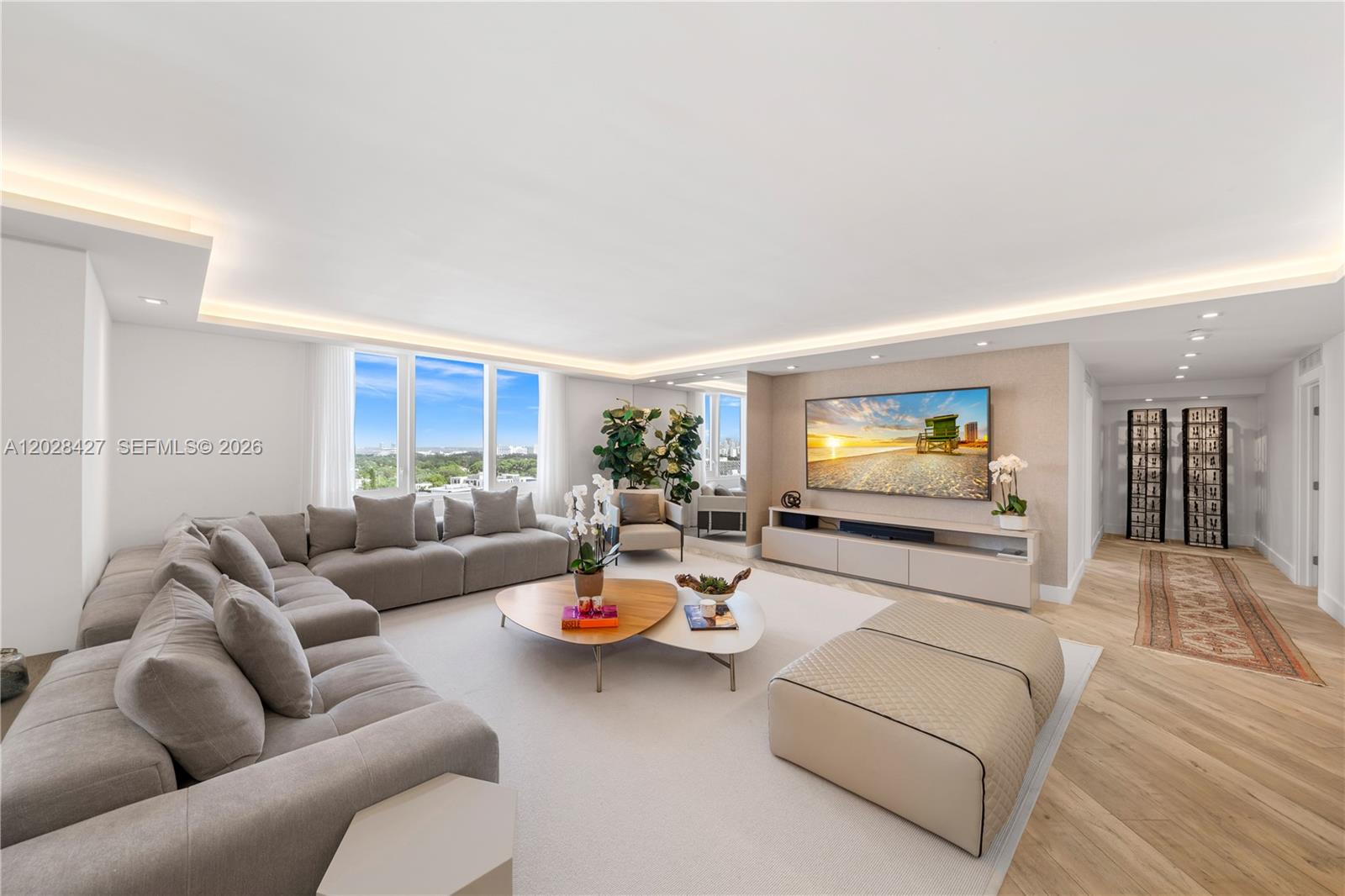 A modern living room features a large sectional sofa, a television, and floor-to-ceiling windows — 2301 Collins Ave # 1432, Miami Beach FL 33139, MIAMI BEACH, FL